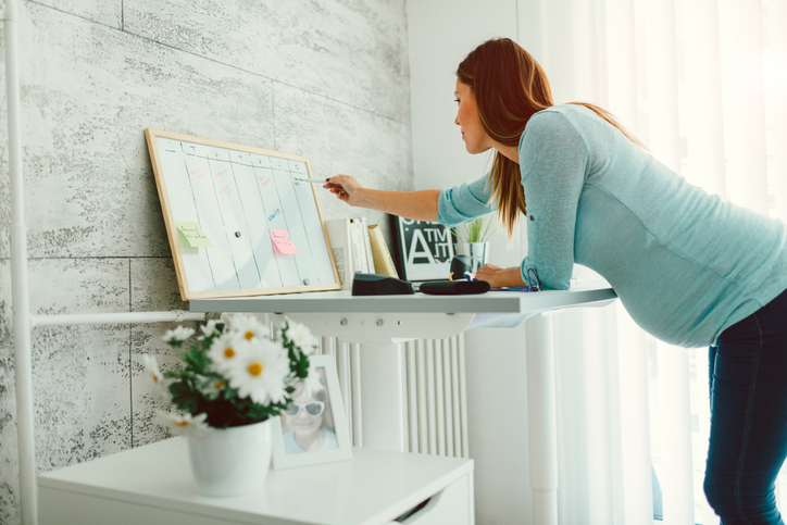 Schwangere Frau liest eine To-Do-Liste auf einer Magnettafel